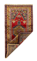 Alfombra roja de estilo oriental con una esquina doblada que muestra el reverso del tejido y sus detalles artesanales