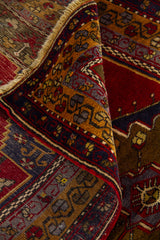 Detalle superior de alfombra artesanal con flecos y composición geométrica en tonos rojo intenso, azul marino y dorado
