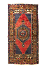 Alfombra oriental rectangular con fondo rojo, detalles azul oscuro y medallón geométrico central