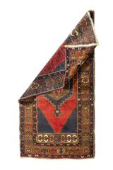 Alfombra oriental roja con una esquina doblada que muestra el reverso del tejido y su diseño tradicional