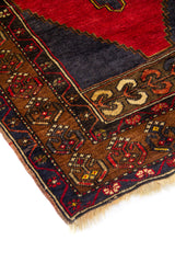 Detalle de esquina de alfombra oriental con borde geométrico en marrón, azul oscuro y rojo