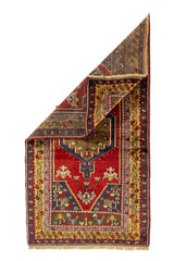 Alfombra oriental roja con una esquina doblada que deja ver el reverso del tejido y su estructura artesanal