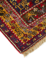 Primer plano de alfombra oriental con motivos geométricos de borde y contraste entre rojo intenso, marrón y azul oscuro