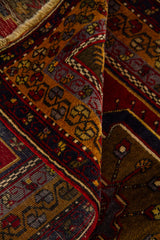 Detalle de alfombra doblada mostrando la textura del tejido, el reverso y la guarda geométrica multicolor