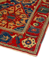 Detalle de esquina de alfombra geométrica roja y azul con borde claro y acabado artesanal