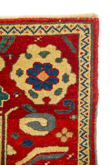 Primer plano de borde de alfombra roja con flor geométrica beige y cenefa angular