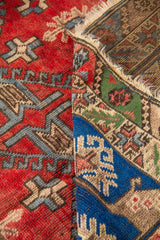 Detalle de alfombra doblada mostrando el grosor, el reverso del tejido y los dibujos geométricos del campo central y la guarda.