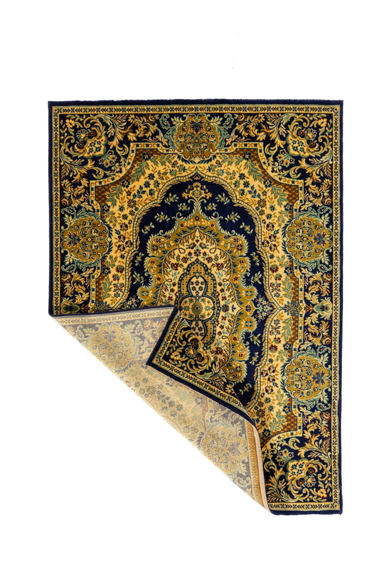 Alfombra clásica en azul marino con una esquina doblada que muestra el reverso, diseño ornamental con medallón central y detalles florales en beige y dorado.