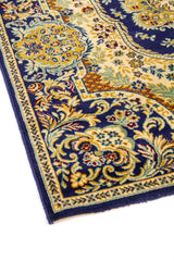 Primer plano del borde de una alfombra oriental azul marino con diseño floral ornamentado y marco decorativo en tonos beige y dorado.