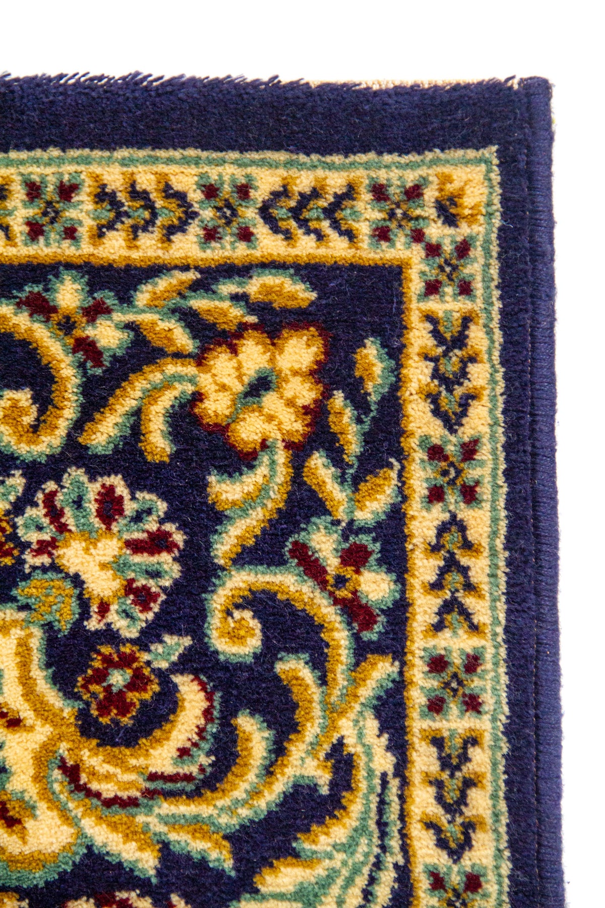 Detalle de esquina de alfombra clásica con fondo azul marino, guardas florales y finos patrones decorativos en beige, dorado y rojo suave.