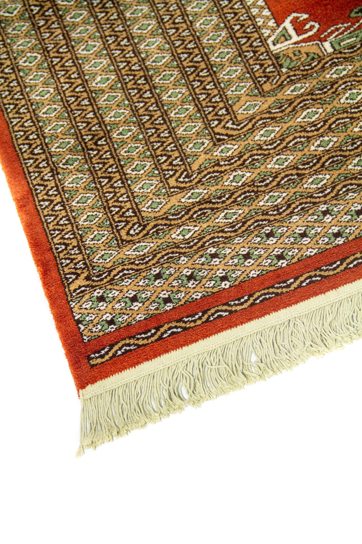 Primer plano de borde de alfombra geométrica con patrones repetitivos en beige, marrón y verde sobre fondo rojo.