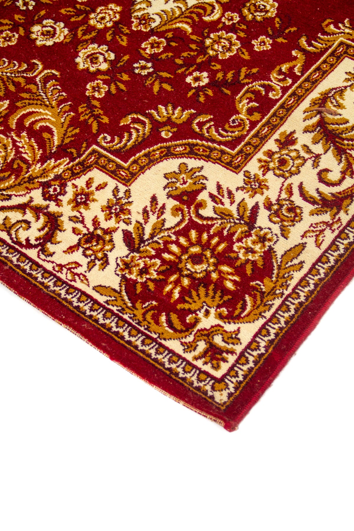 Detalle en perspectiva de esquina de alfombra roja con fondo blanco suave, patrones florales elegantes y borde decorativo fino.