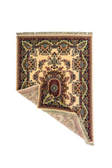 Alfombra persa color blanco suave con esquina doblada, mostrando el reverso y destacando su elaborado diseño floral, medallón central y borde decorativo en azul, rojo y beige.