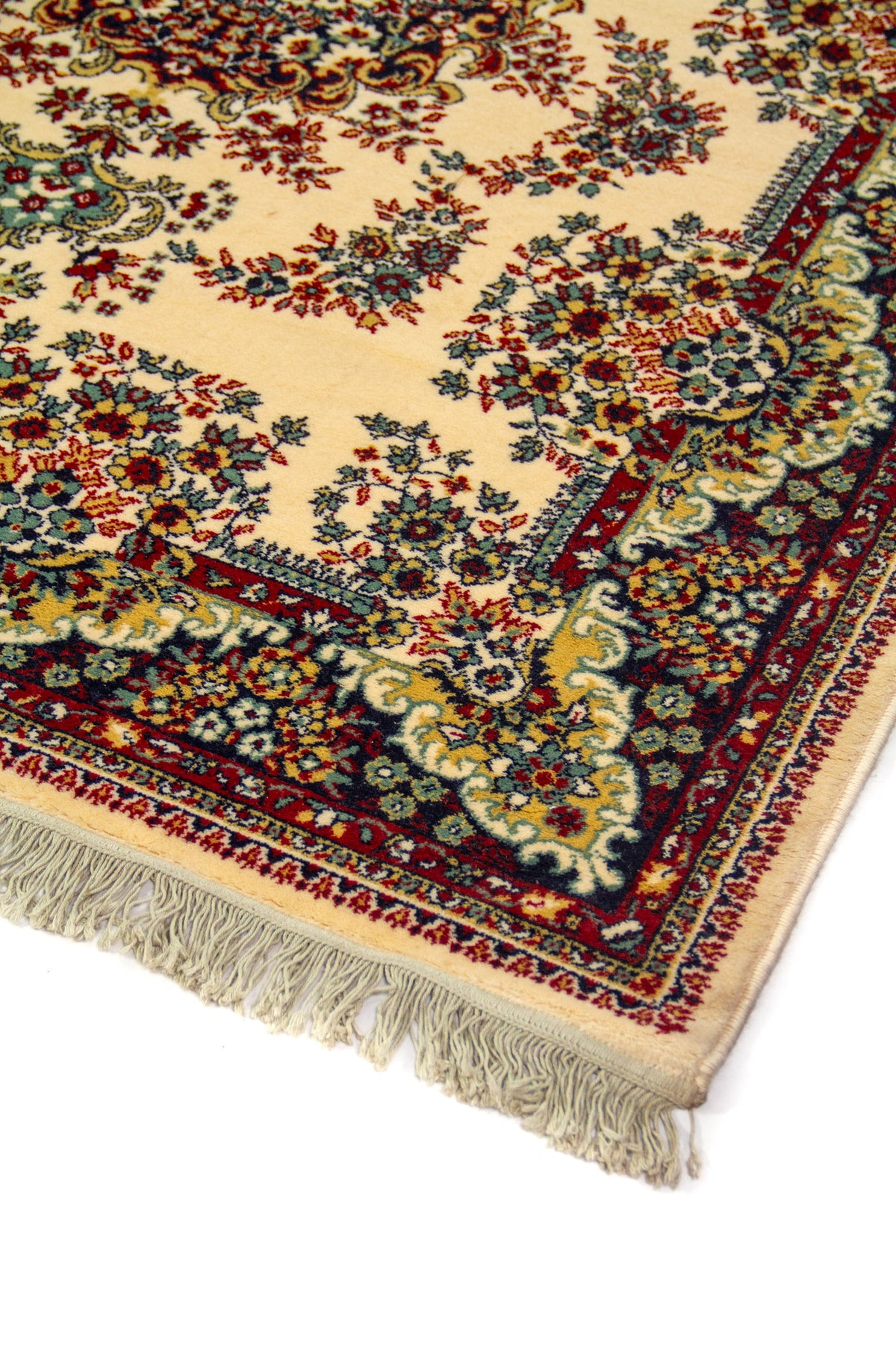 Detalle de esquina de alfombra clásica con fondo blanco suave, motivos florales minuciosos, guarda azul oscuro y roja, y flecos claros en el borde inferior