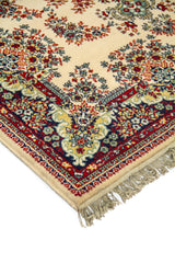 Primer plano de esquina de alfombra ornamental con diseño floral tradicional, fondo claro y combinación de azul marino, rojo profundo, beige y celeste.