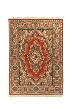 Alfombra oriental rectangular en tono rojo con medallón central blanco suave y detalles florales en azul suave, beige y negro, enmarcada por una guarda ancha con rosetones ornamentales y flecos en los extremos.