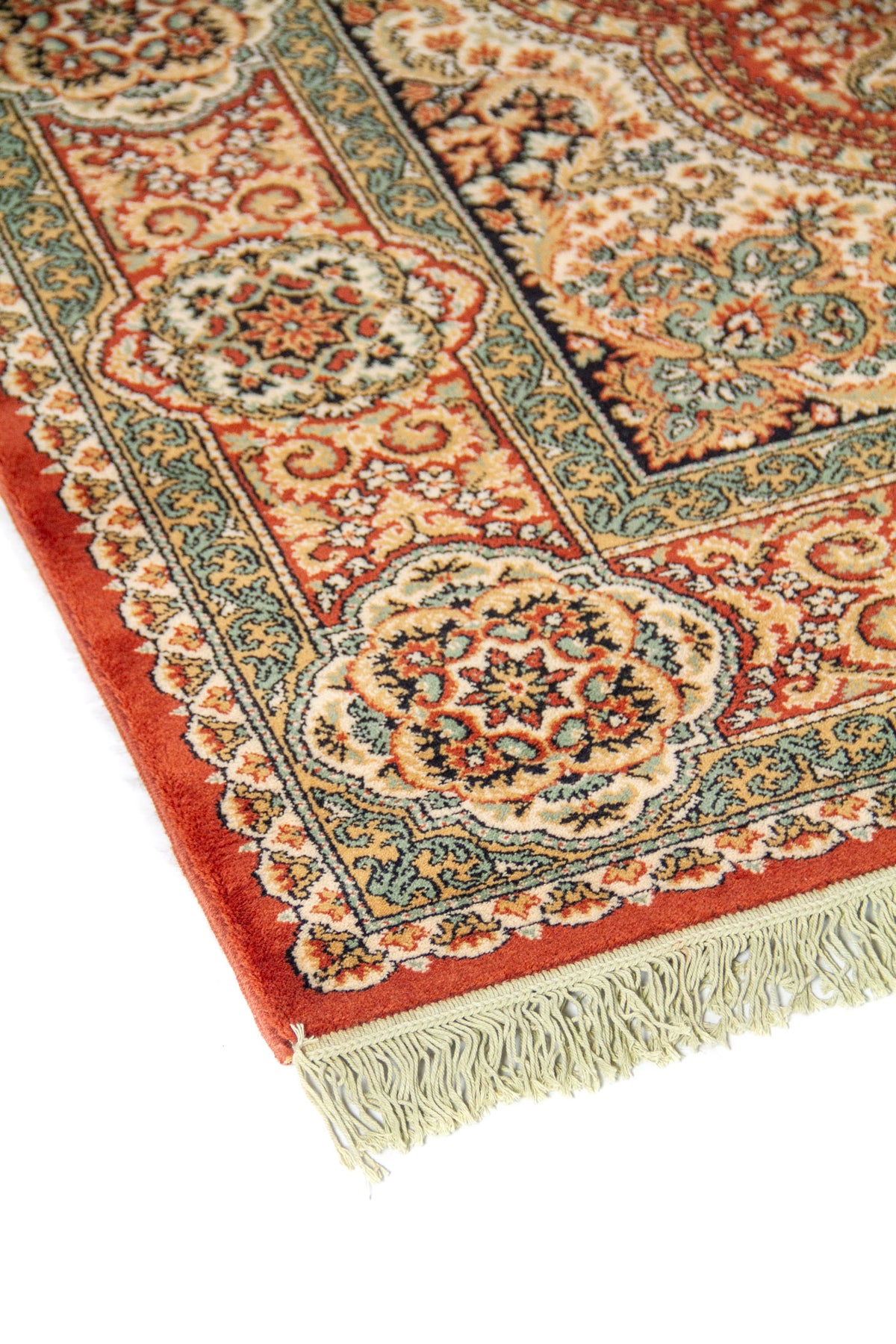 Primer plano del borde de una alfombra tradicional con cenefa ornamental, medallones circulares repetidos y finos motivos florales en tonos cálidos y azulados.