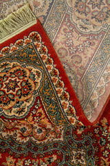 Detalle de la alfombra doblada con vista parcial del reverso, resaltando el grosor, la terminación de los flecos y la riqueza del diseño ornamental.