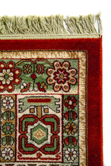 Primer plano de la esquina superior de alfombra oriental con flores decorativas, marco geométrico en tonos suaves y borde rojo profundo.