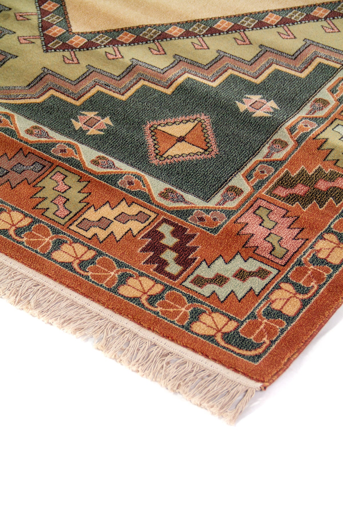 Detalle de esquina de alfombra tradicional con guarda geométrica en tonos rojo, beige, verde oscuro y rosa, y flecos color blanco suave.