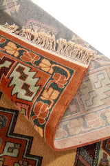 Detalle de alfombra doblada mostrando el reverso tejido, la textura del pelo y los motivos geométricos del diseño.