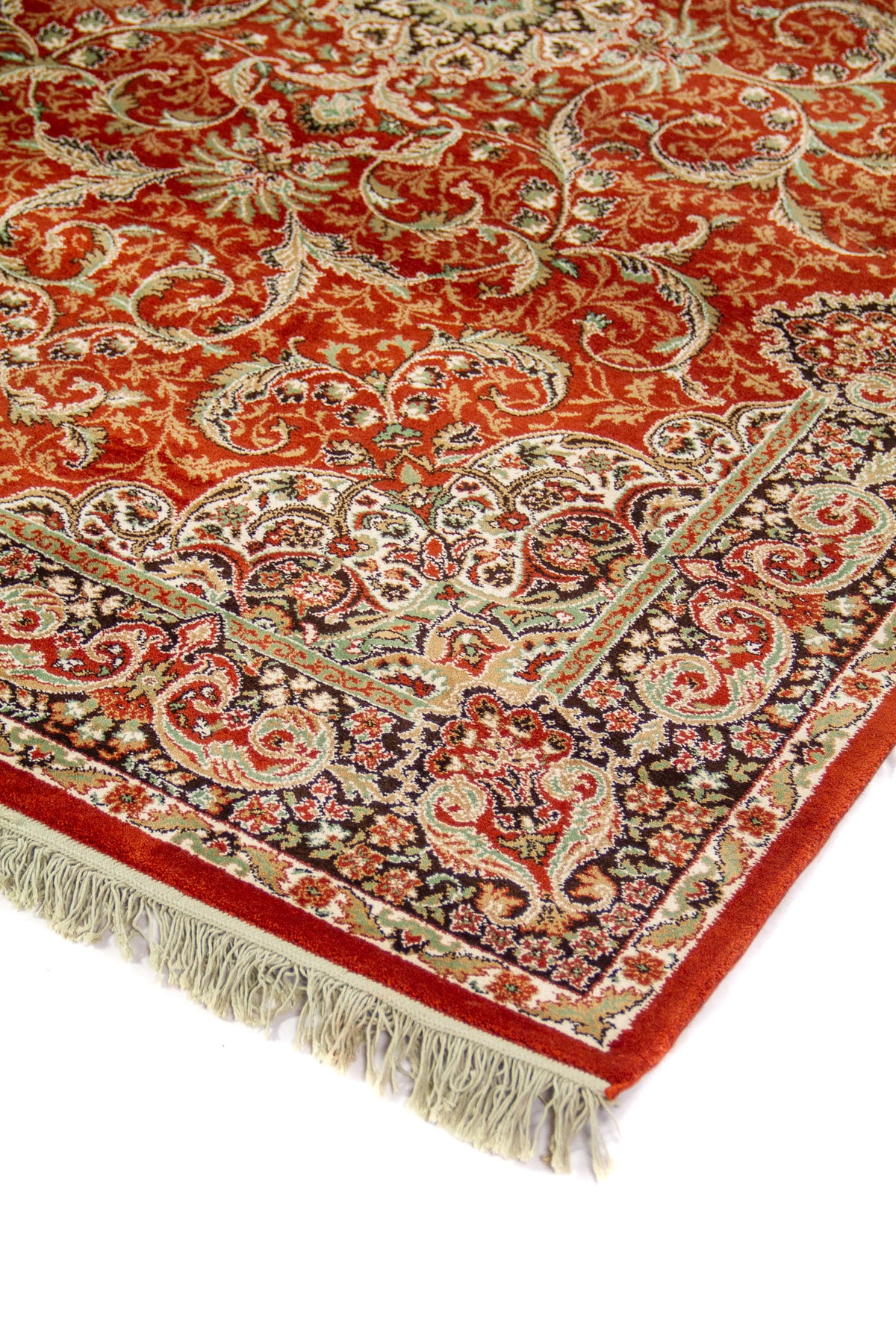 Detalle de esquina de alfombra oriental en color anaranjado suave con guarda negra, motivos florales y flecos blanco suave