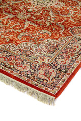 Detalle de esquina de alfombra oriental en color anaranjado suave con guarda negra, motivos florales y flecos blanco suave