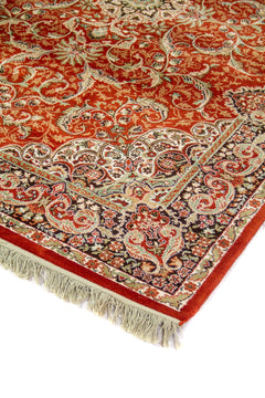 Detalle de esquina de alfombra oriental en color anaranjado suave con guarda negra, motivos florales y flecos blanco suave