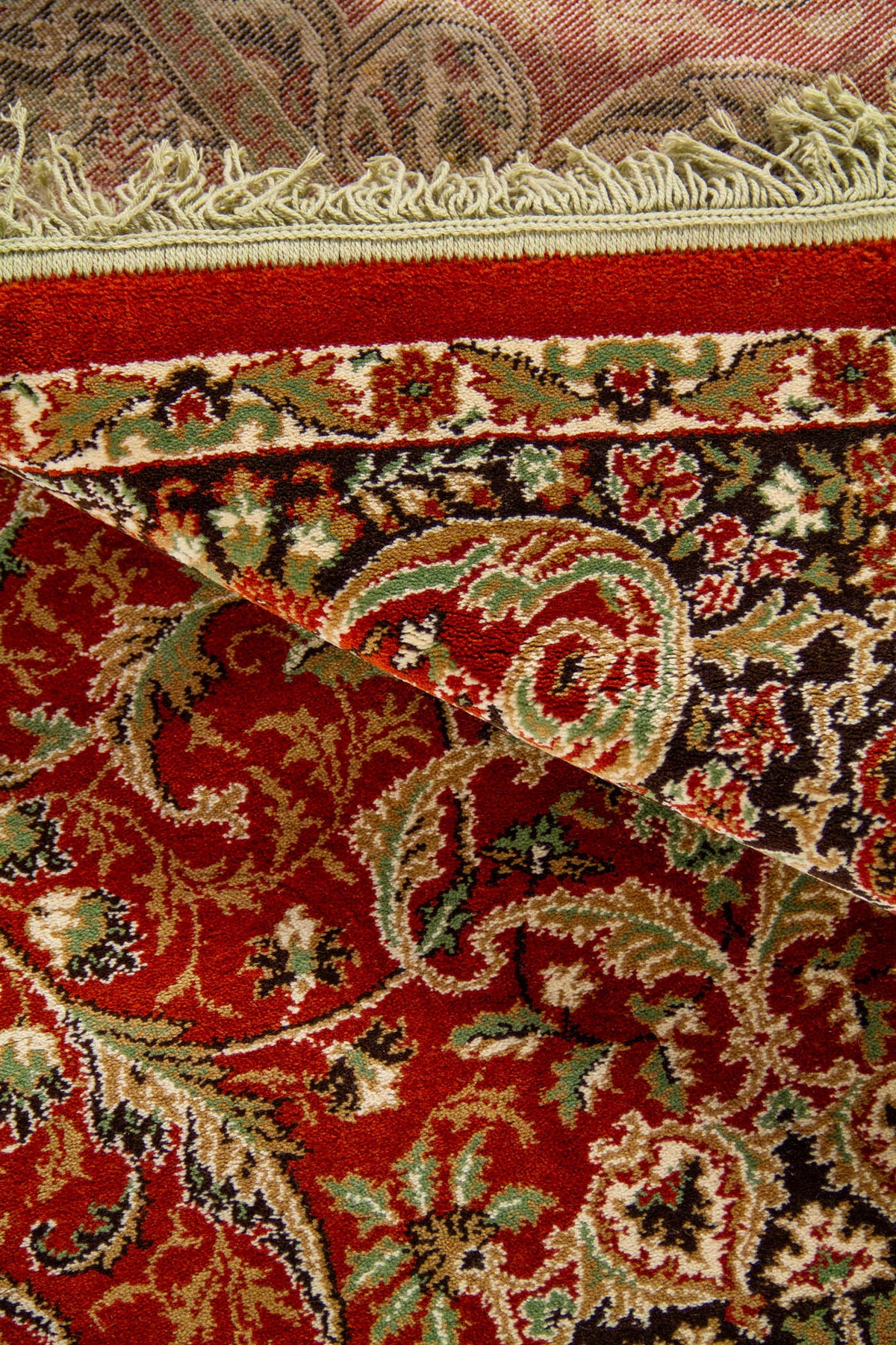 Detalle de textura y reverso de alfombra oriental anaranjado suave con diseño floral, borde decorativo y flecos en color blanco suave