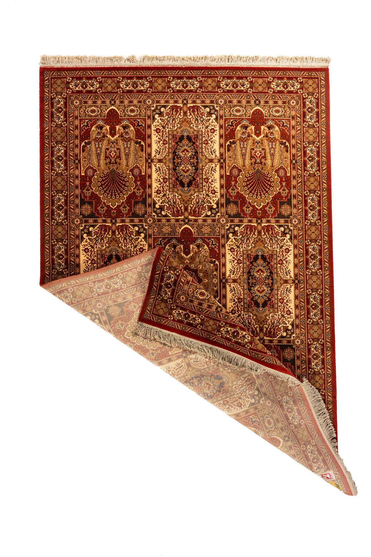 Alfombra oriental roja con una esquina doblada que muestra el reverso, detalle de su estructura textil, cenefas decorativas y flecos beige.