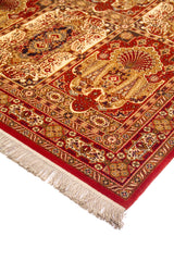Detalle en perspectiva de alfombra clásica roja con motivos ornamentales, guarda floral y flecos claros en el borde inferior.