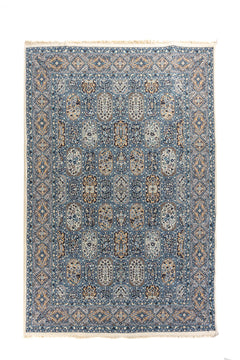 Alfombra oriental en tonos azul, beige y blanco suave  con diseño de paneles florales y guarda geométrica, vista completa