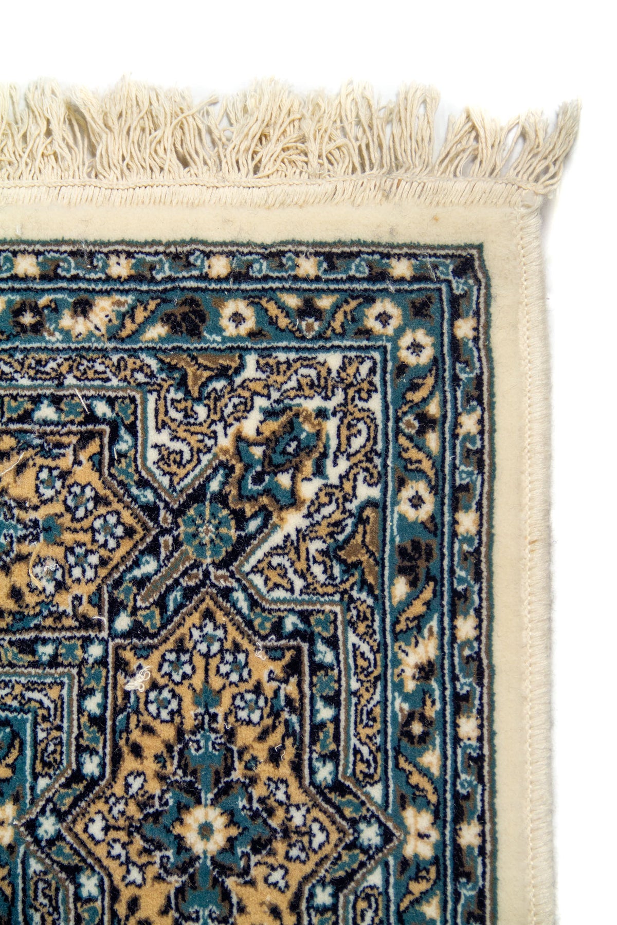 Acercamiento al borde superior de la alfombra, destacando la guarda con motivos geométricos estrellados y ornamentos florales. Esta imagen permite apreciar la fineza del diseño y su cuidada composición.