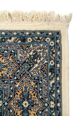 Acercamiento al borde superior de la alfombra, destacando la guarda con motivos geométricos estrellados y ornamentos florales. Esta imagen permite apreciar la fineza del diseño y su cuidada composición.