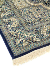 Detalle de esquina de alfombra oriental azul con flecos claros, borde oscuro y motivos florales