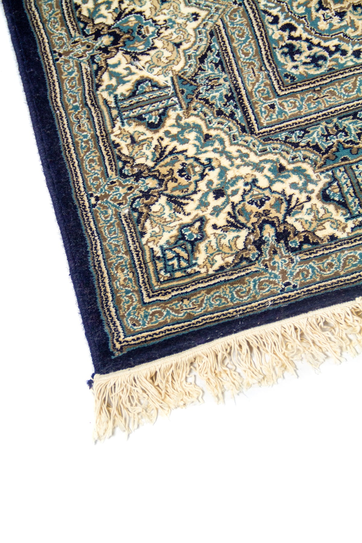 Acercamiento de borde de alfombra azul oscuro y beige con guarda floral y ornamentos simétricos