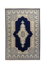 Alfombra oriental rectangular en tonos azul oscuro, blanco suave y celeste, con gran campo central azul oscuro, medallón alargado y guarda floral detallada.