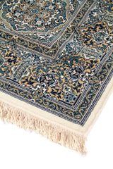 Primer plano del borde de una alfombra oriental con diseño floral clásico, guardas decorativas y flecos claros en tono blanco suave.