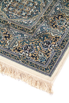 Primer plano del borde de una alfombra oriental con diseño floral clásico, guardas decorativas y flecos claros en tono blanco suave.