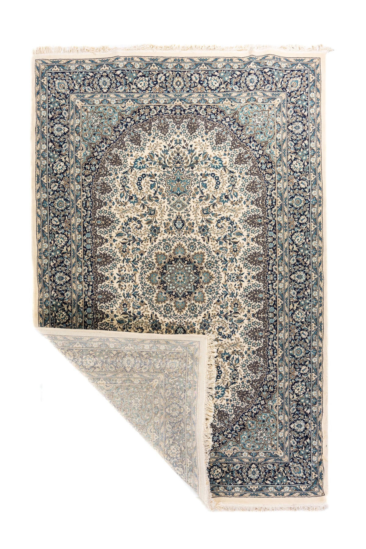 Alfombra oriental en tonos blanco suave y azul con una esquina doblada que muestra el reverso, los flecos y el detalle del tejido.