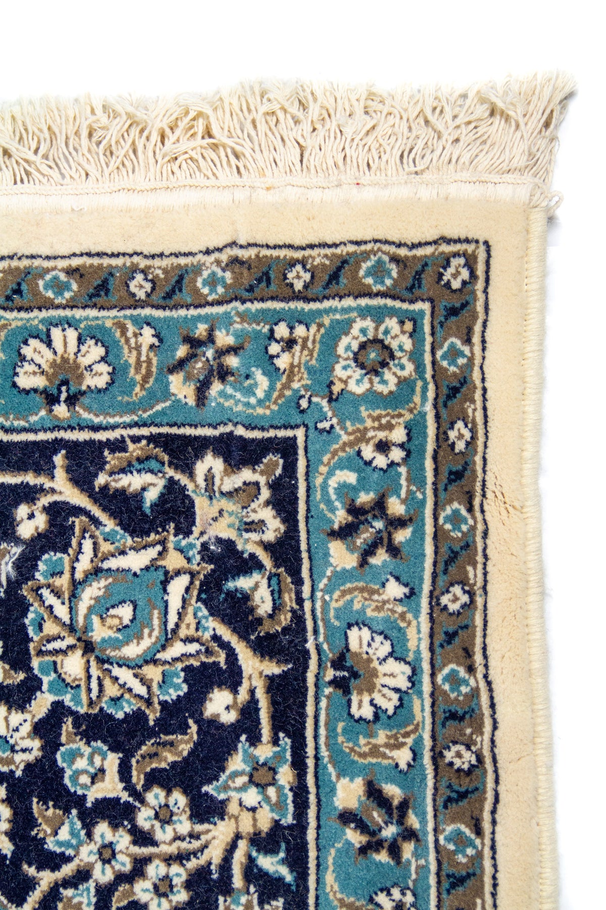 Primer plano de esquina de alfombra ornamental con borde blanco suave y diseño floral en tonos azul, celeste y beige