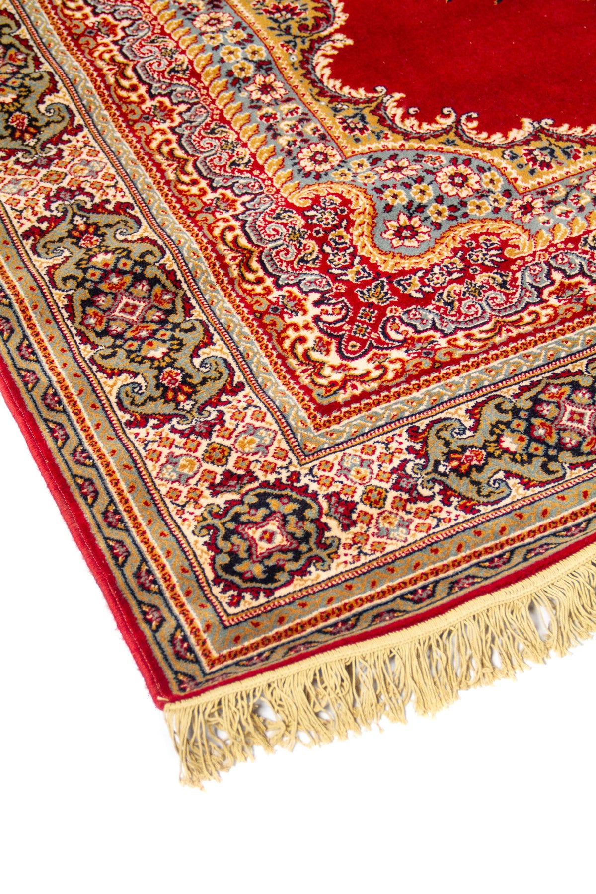 Acercamiento lateral de alfombra oriental roja con motivos florales curvos, cenefa decorativa y terminación con flecos beige.