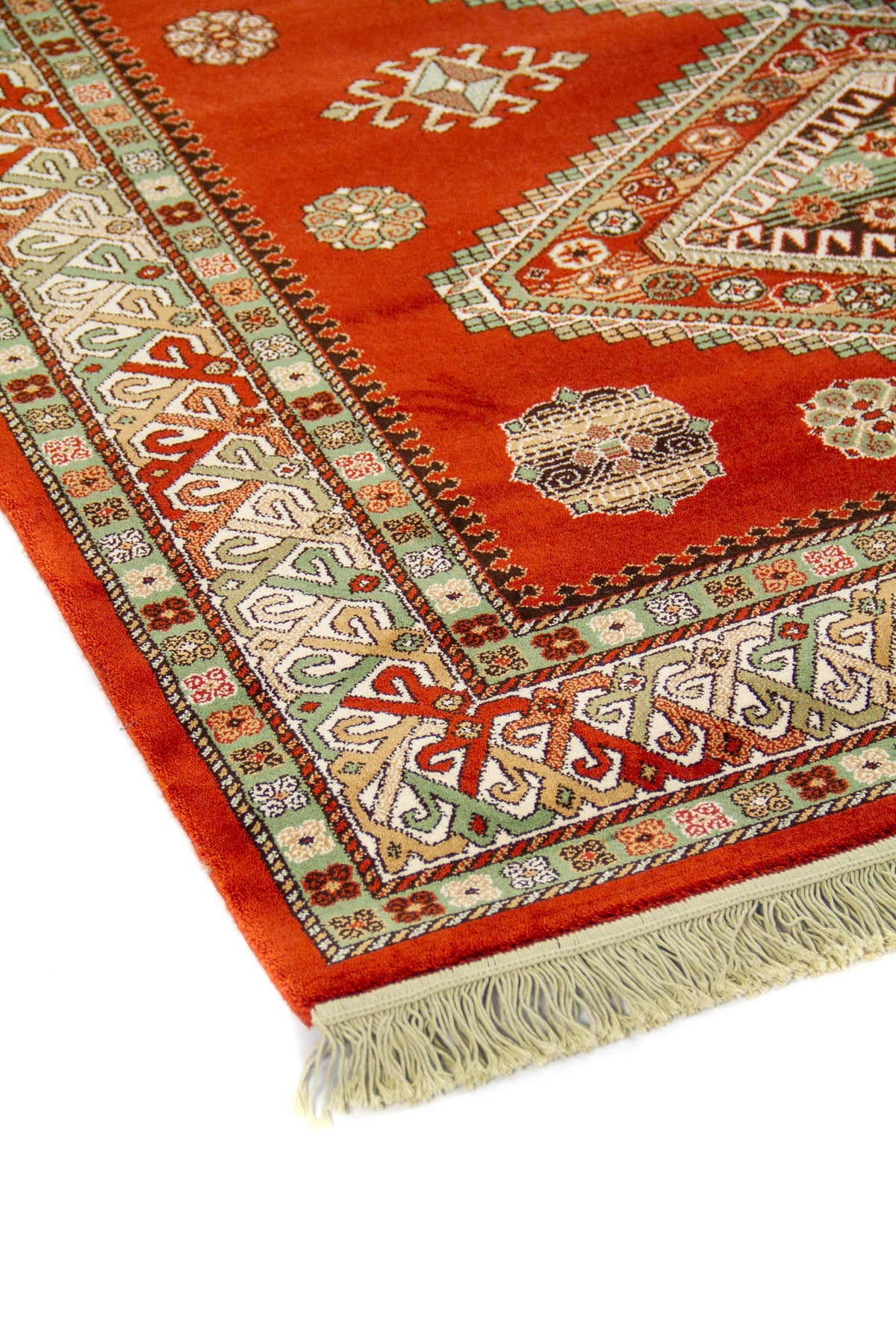 Primer plano del borde de alfombra oriental con fondo rojo, motivos geométricos tradicionales y terminación con flecos