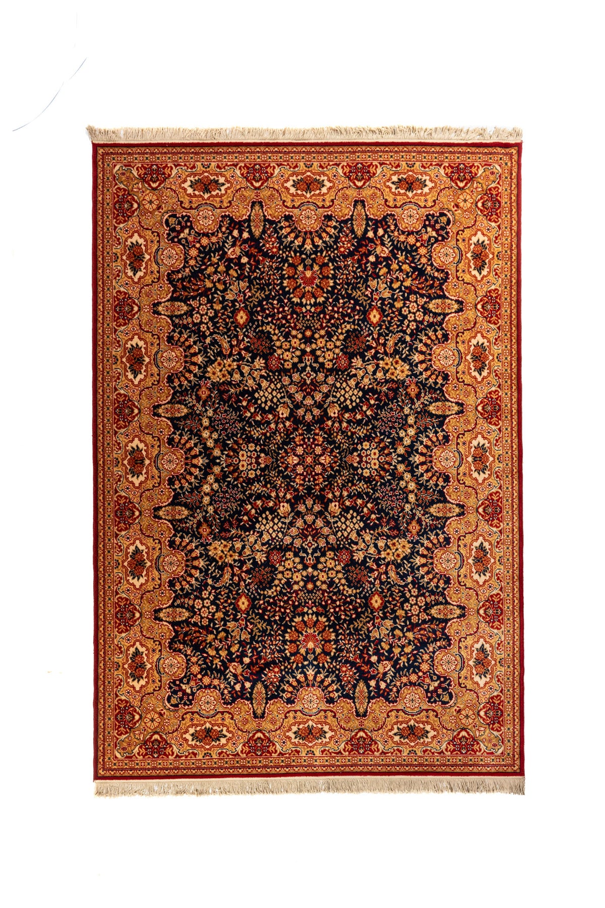 Alfombra clásica oriental en tonos azul oscuro, dorado, rojo y beige con diseño floral denso, guarda ornamental ancha y flecos en los extremos.