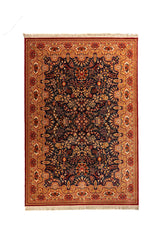 Alfombra clásica oriental en tonos azul oscuro, dorado, rojo y beige con diseño floral denso, guarda ornamental ancha y flecos en los extremos.