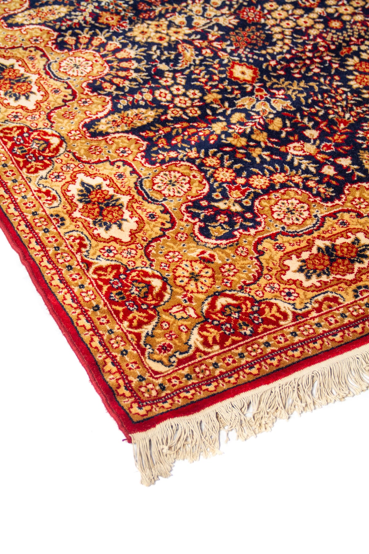 Acercamiento lateral de alfombra oriental floral con guarda dorada, detalles en rojo y beige, y terminación con flecos en el extremo.