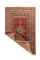 Alfombra oriental clásica con una esquina doblada que muestra el reverso, la estructura del tejido, los flecos beige y el borde decorativo.