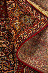 Detalle de alfombra oriental parcialmente doblada que deja ver el reverso, la textura del tejido y la riqueza del diseño geométrico y floral del borde.