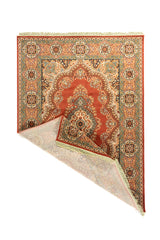 Alfombra tradicional en tonos cálidos con una esquina doblada que deja ver el reverso tejido, los flecos color blanco suave y el detalle del borde decorativo.