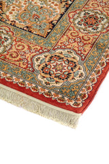 Detalle de esquina de alfombra oriental con guarda floral en tonos rojo, beige y celeste, acabado aterciopelado y flecos color blanco suave.